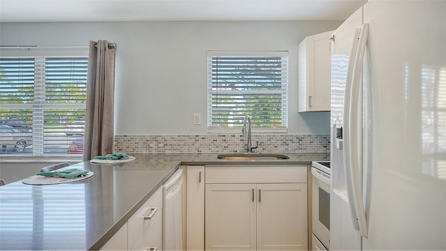 kitchen featuring decorative backsplash, sink, white cabinets, and white appliances