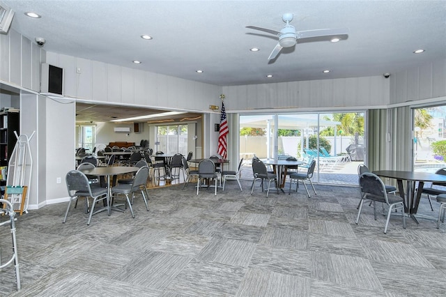 carpeted dining area with ceiling fan and a wall unit AC