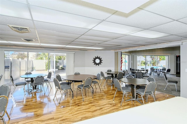 dining area featuring hardwood / wood-style floors, a paneled ceiling, and a wealth of natural light