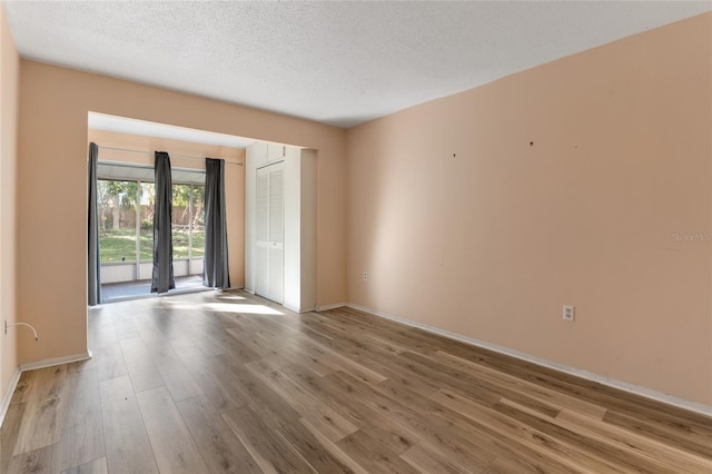 unfurnished room with a textured ceiling and light hardwood / wood-style flooring