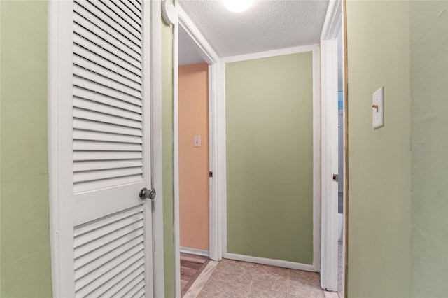 corridor featuring a textured ceiling and light tile patterned flooring