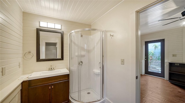 bathroom with ceiling fan, hardwood / wood-style floors, a shower with door, vanity, and ornamental molding