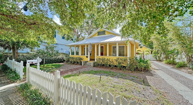 bungalow-style home with a porch, fence, and metal roof
