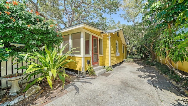 view of side of property with metal roof, entry steps, and aphalt driveway