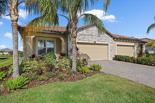 2520 Avolet Ct, Bradenton, FL 34211 - view of front facade with stucco siding, a garage, decorative driveway, a front lawn, and stone siding