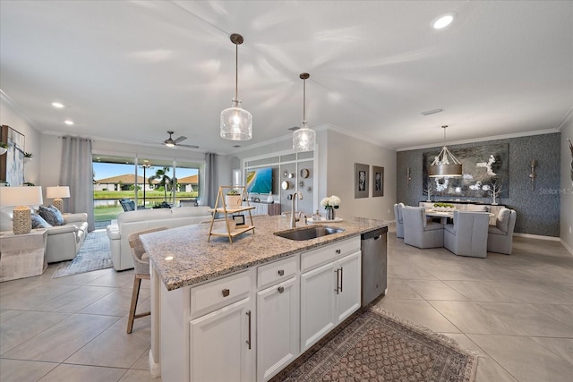 kitchen featuring sink, hanging light fixtures, stainless steel dishwasher, an island with sink, and white cabinetry