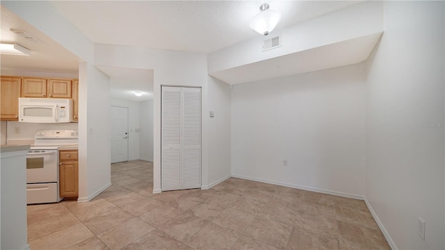 kitchen featuring light brown cabinetry, white appliances, and light tile patterned floors