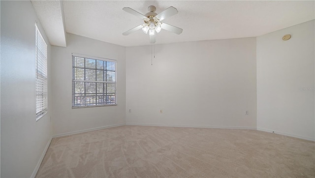 empty room with light carpet, ceiling fan, and a textured ceiling