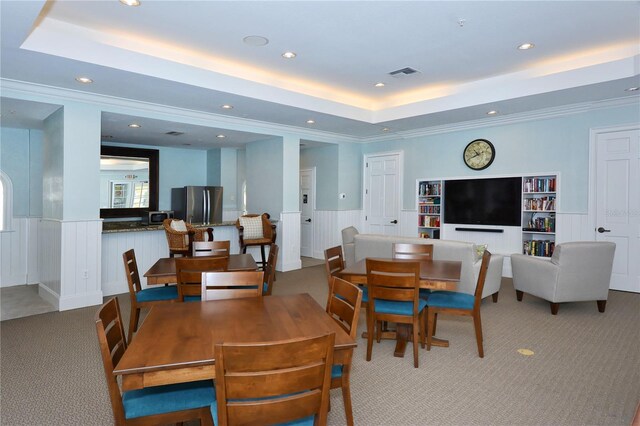 dining space with ornamental molding, a tray ceiling, and light colored carpet