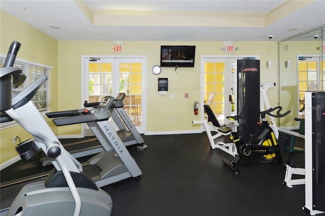 exercise room with french doors and a tray ceiling