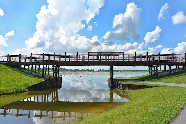 view of dock with a water view and a yard