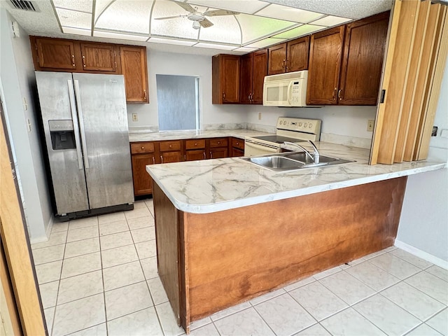 kitchen with white appliances, kitchen peninsula, sink, and light tile patterned floors