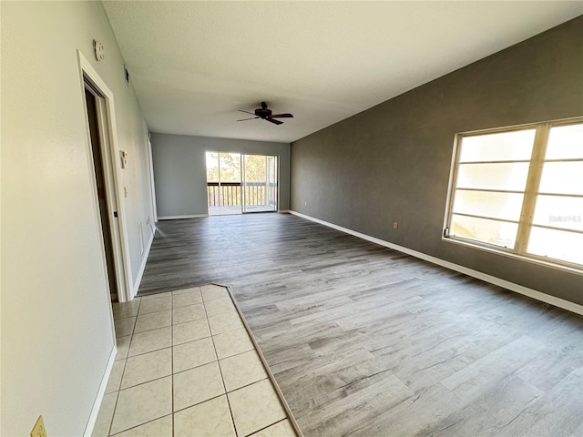 empty room with ceiling fan, a textured ceiling, and light hardwood / wood-style flooring