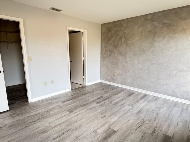 unfurnished bedroom featuring a walk in closet, a closet, and light hardwood / wood-style flooring