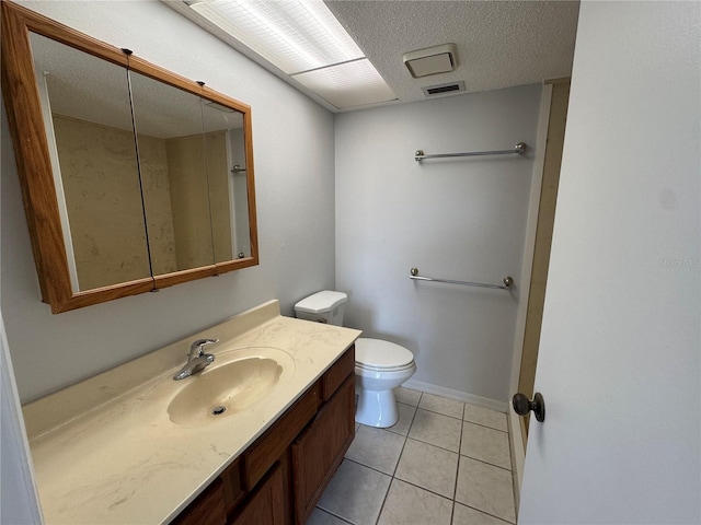 bathroom with tile patterned floors, vanity, a textured ceiling, and toilet