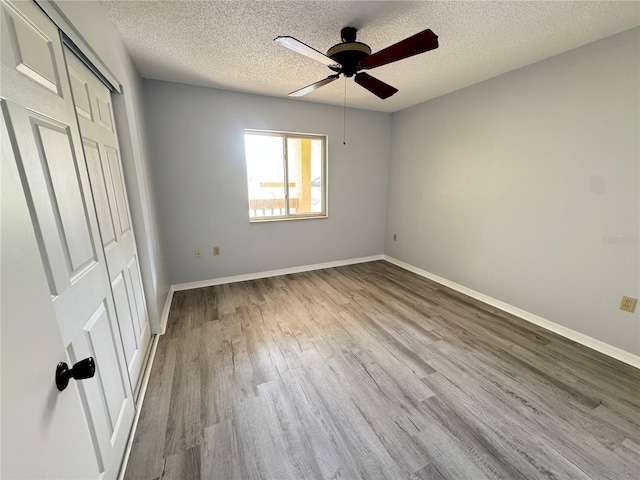 unfurnished bedroom featuring ceiling fan, a closet, light hardwood / wood-style floors, and a textured ceiling