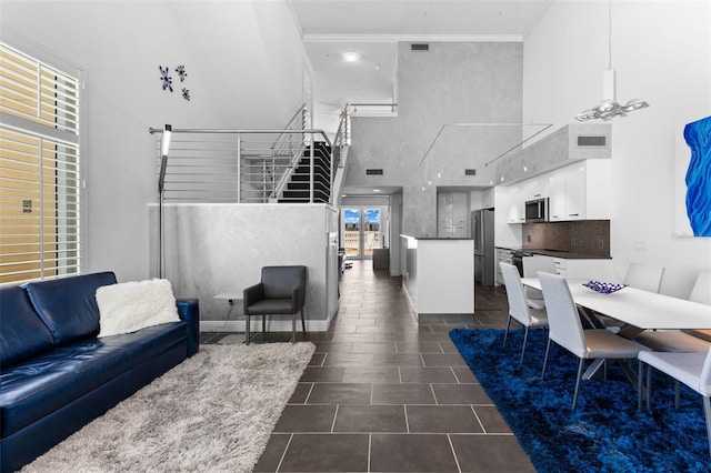 tiled living room with ceiling fan, a towering ceiling, crown molding, and a wealth of natural light