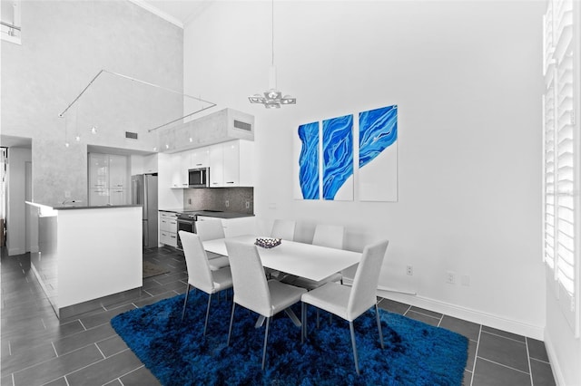 dining space featuring dark tile patterned flooring, a high ceiling, and ornamental molding