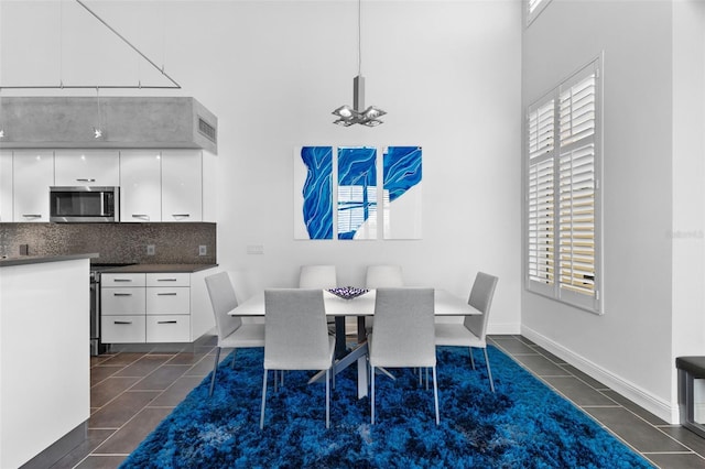 dining area featuring dark tile patterned floors and a high ceiling