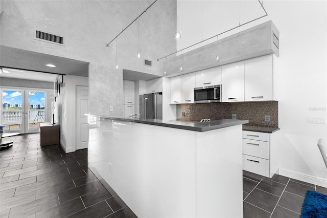 kitchen featuring ceiling fan, a towering ceiling, white cabinetry, kitchen peninsula, and stainless steel appliances