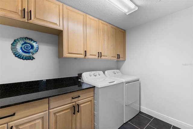 washroom with cabinets, a textured ceiling, washing machine and dryer, and dark tile patterned flooring