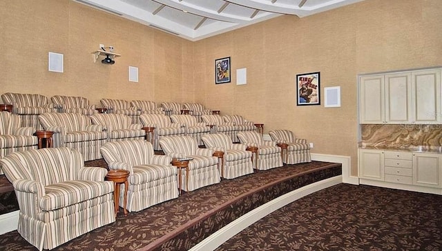 carpeted home theater room with coffered ceiling