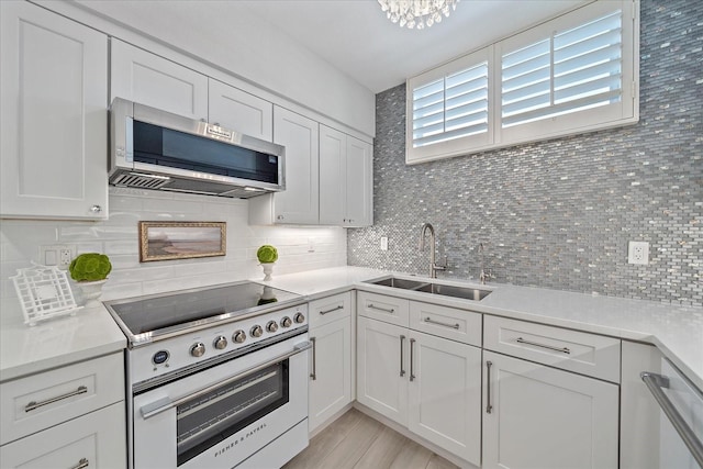 kitchen featuring tasteful backsplash, stainless steel appliances, sink, light hardwood / wood-style floors, and white cabinetry