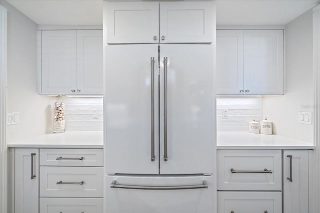 kitchen with high end refrigerator, backsplash, and white cabinetry