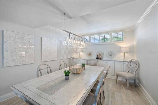 dining space with a notable chandelier, crown molding, and light wood-type flooring