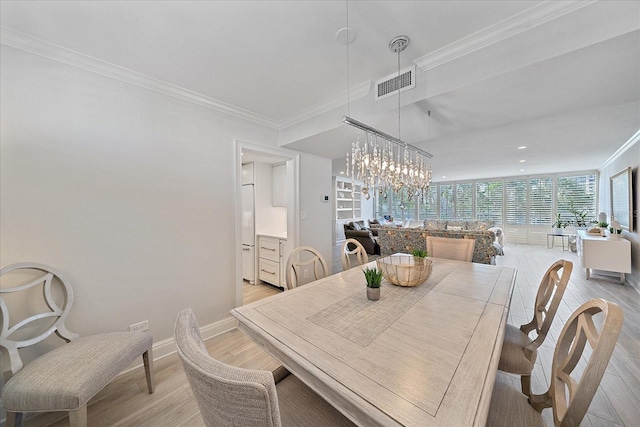 dining room featuring crown molding, light hardwood / wood-style flooring, and an inviting chandelier