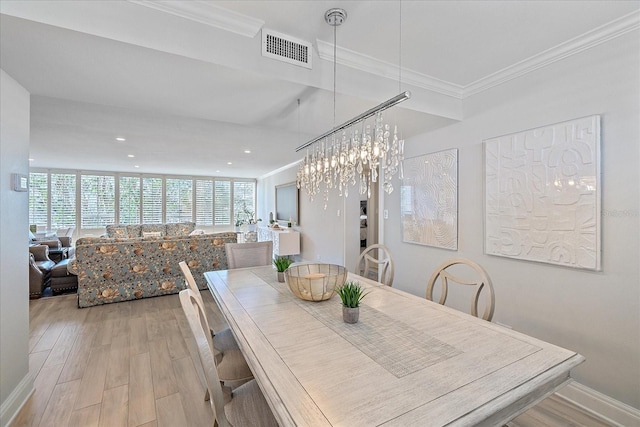 dining space featuring an inviting chandelier, light hardwood / wood-style flooring, and crown molding