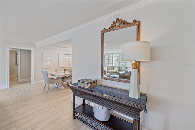 corridor with light hardwood / wood-style floors, a notable chandelier, and ornamental molding