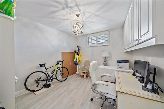 office with light hardwood / wood-style flooring and a notable chandelier