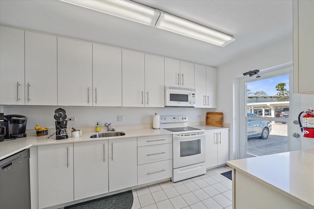 kitchen with sink, white cabinets, white appliances, and light tile patterned floors