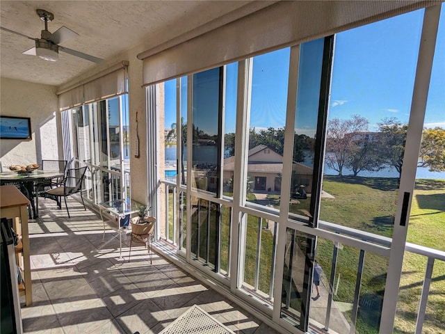 sunroom featuring ceiling fan and a water view