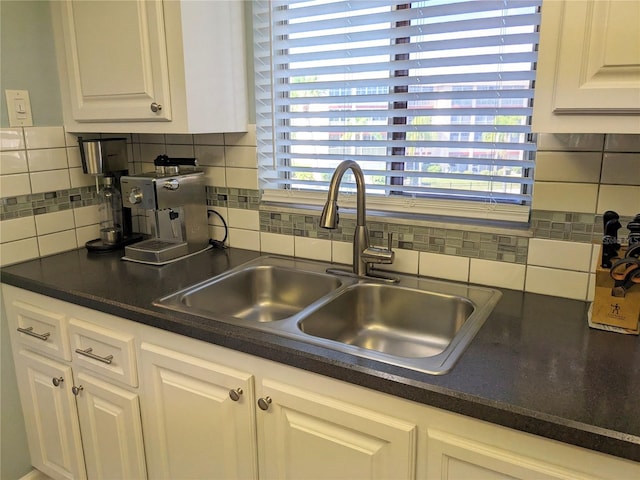 kitchen featuring tasteful backsplash, white cabinetry, and sink