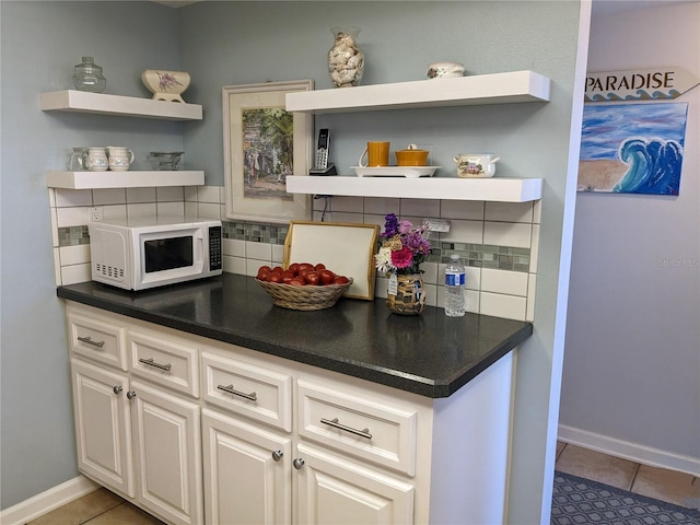 kitchen with white cabinets, light tile patterned floors, and backsplash