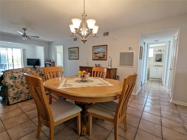 tiled dining space with ceiling fan with notable chandelier and a textured ceiling