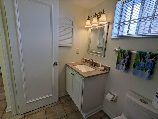 bathroom with toilet, vanity, and tile patterned floors