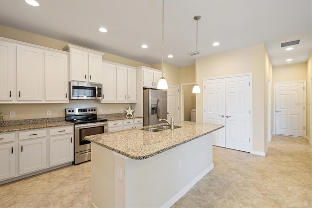 kitchen with pendant lighting, a kitchen island with sink, white cabinets, sink, and appliances with stainless steel finishes