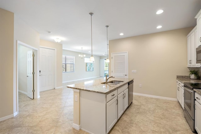 kitchen with light stone countertops, stainless steel appliances, sink, a center island with sink, and white cabinetry