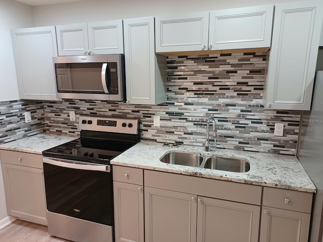 kitchen with white cabinets, sink, stainless steel appliances, and tasteful backsplash