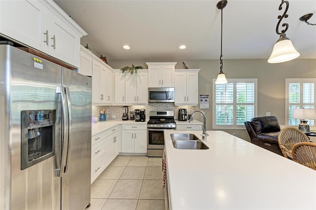 kitchen featuring white cabinets, decorative light fixtures, sink, and appliances with stainless steel finishes