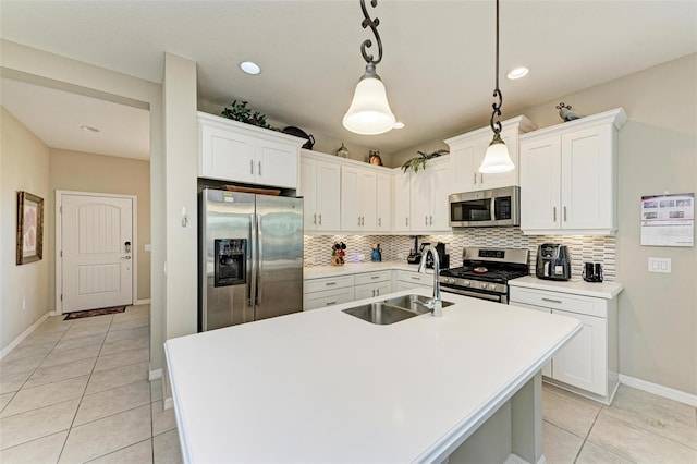 kitchen with appliances with stainless steel finishes, sink, pendant lighting, a center island with sink, and white cabinets