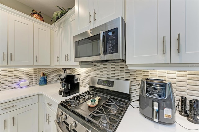 kitchen with white cabinets, appliances with stainless steel finishes, and backsplash