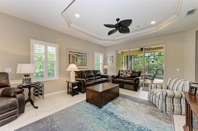 living room with a tray ceiling, ceiling fan, crown molding, and light tile patterned floors