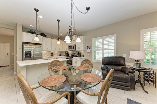 dining space featuring sink, light tile patterned flooring, plenty of natural light, and a notable chandelier