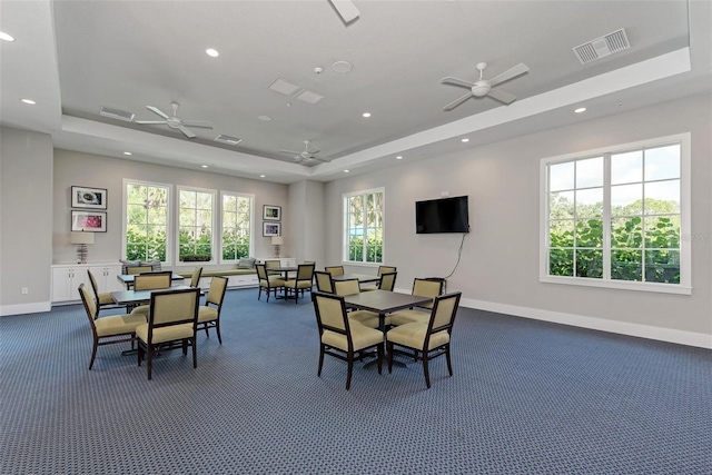 dining room featuring dark colored carpet, ceiling fan, and a tray ceiling