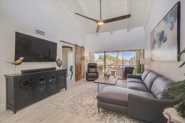 living room featuring light wood-type flooring, ceiling fan, a barn door, high vaulted ceiling, and beamed ceiling