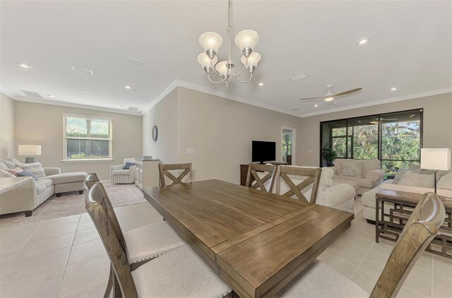 tiled dining space featuring a healthy amount of sunlight, ceiling fan with notable chandelier, and ornamental molding